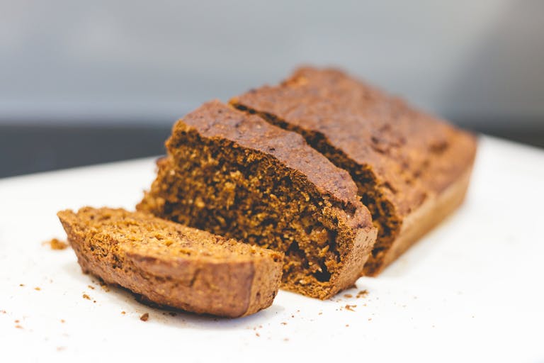 Delicious homemade banana bread sliced on a white surface with a rustic texture.