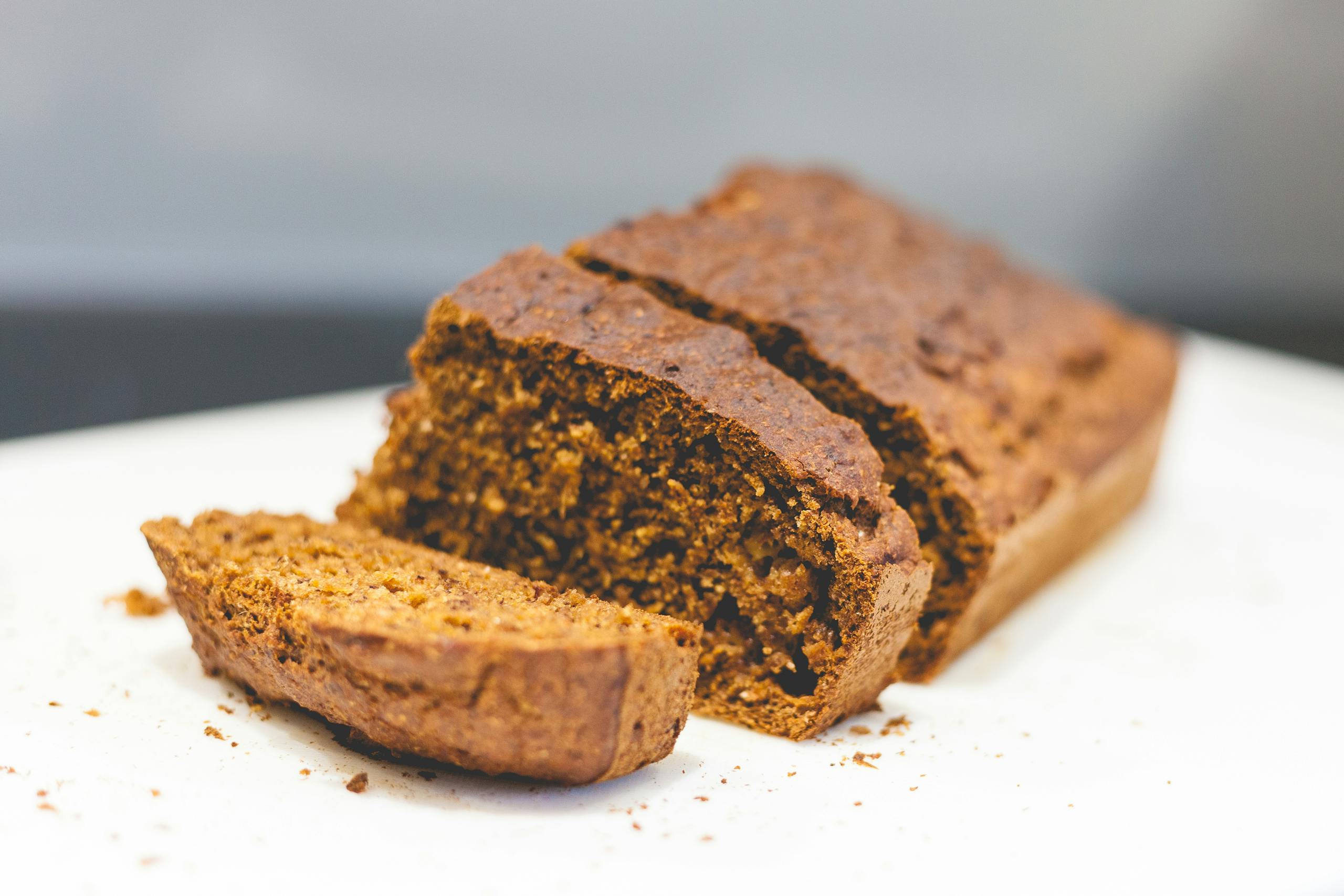 Delicious homemade banana bread sliced on a white surface with a rustic texture.